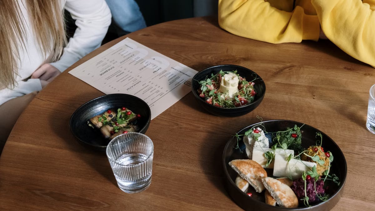 Casual meal setting with assorted dishes and beverages on a wooden table, featuring diverse food options.