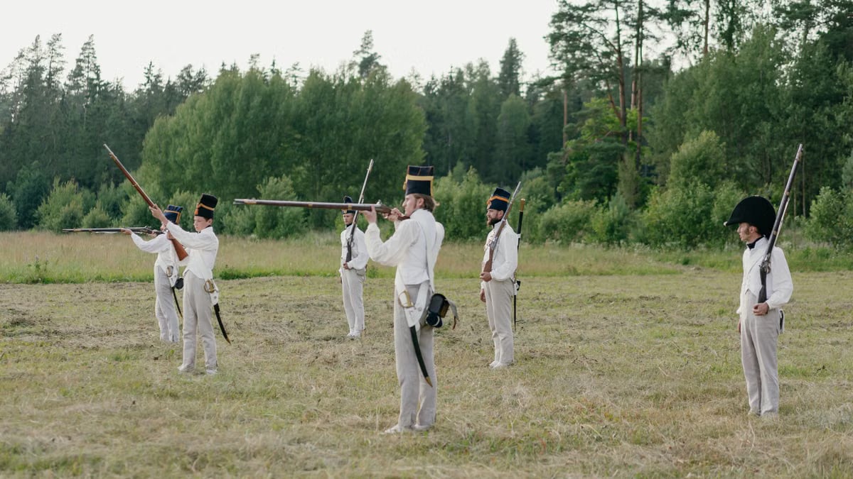Group of soldiers practicing historical battlefield reenactment outdoors.